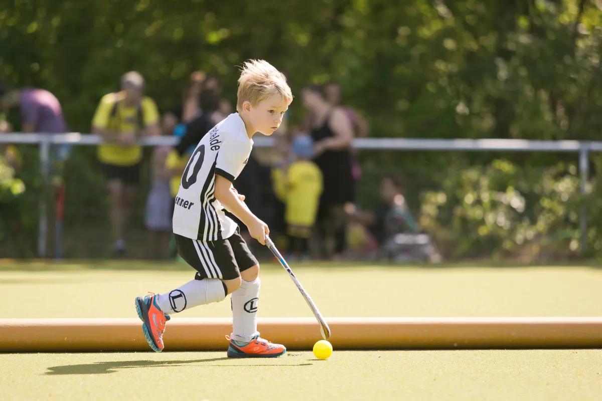 Ein Kind mit Hockeyschläger und Ball
